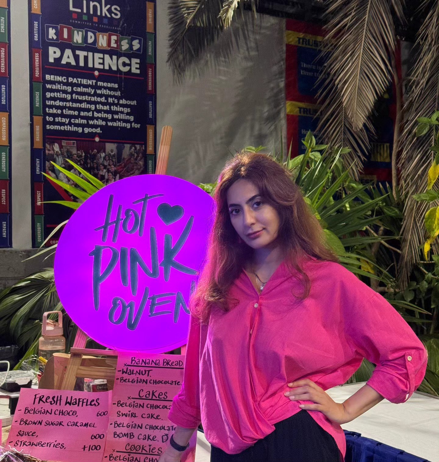 The lit pink Hot Pink Oven sign at a pop-up table